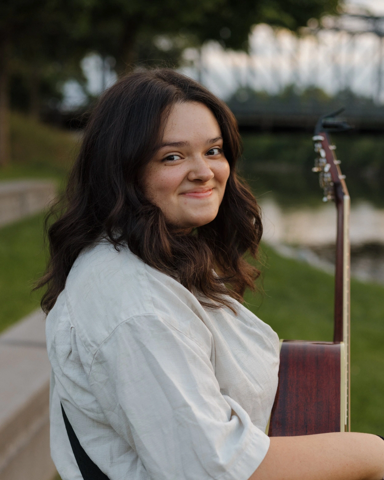 Senior portrait with guitar near a bridge at sunset